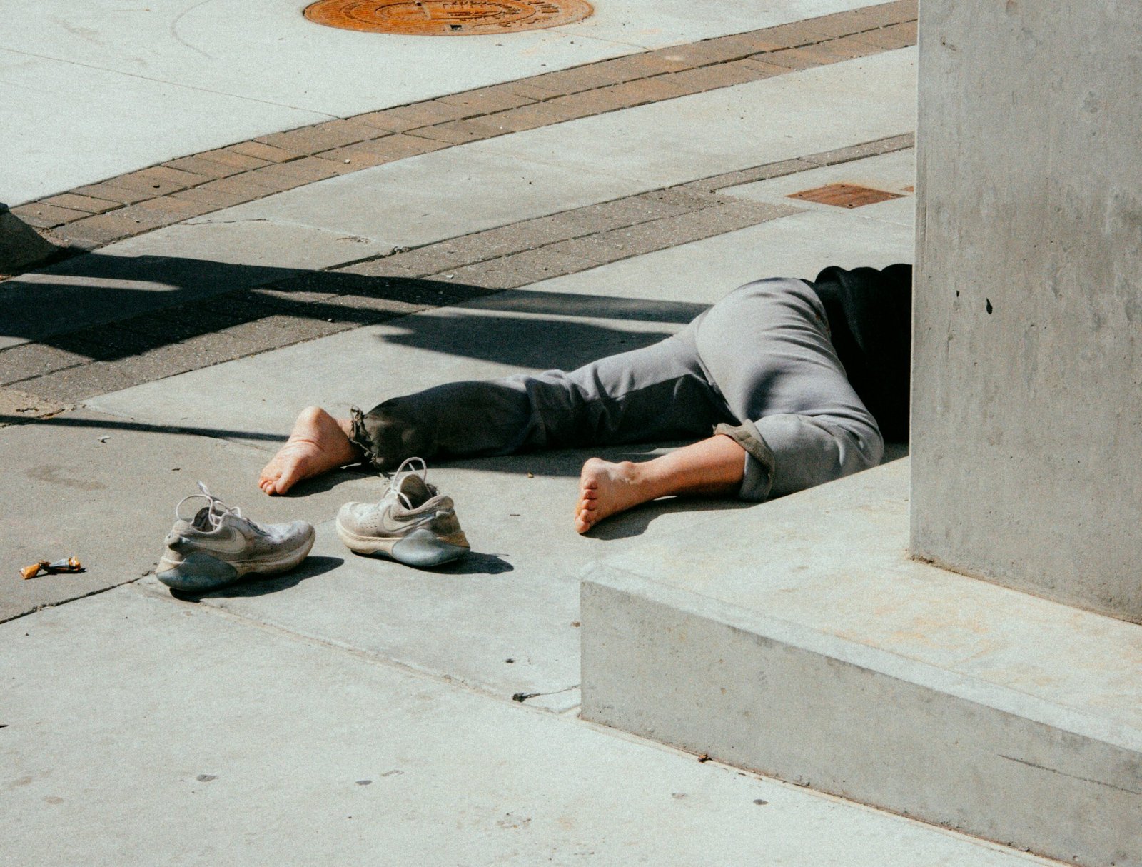 person in gray pants and gray shoes sitting on concrete bench